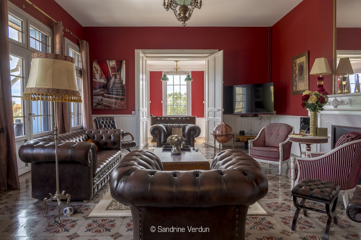 Salon d'un château avec canapés en cuir élégants et accès aux chambres d'hôtes de prestige